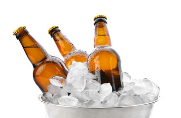 Bowl with bottles of beer in ice on white background