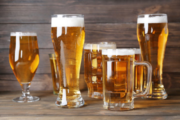 Glassware with fresh beer on wooden background