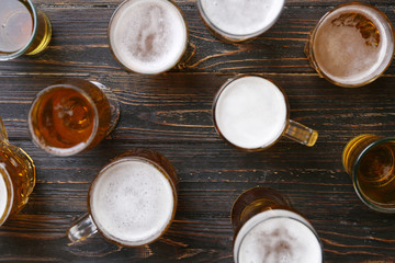 Glassware with fresh beer on wooden background, top view