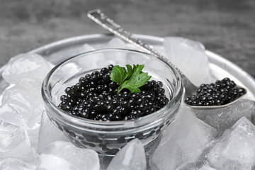 Black caviar served with ice on metal tray, closeup