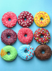 Delicious colorful donuts on color background