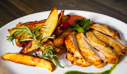 Grilled chicken breast with potato in a plate on wooden table