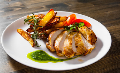 Grilled chicken breast with potato in a plate on wooden table