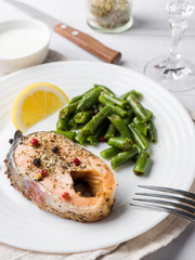 Healthy food. Baked red fish, pink salmon, salmon and green beans with a slice of lemon on a plate.