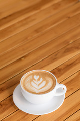 Hot rose Latte art coffee white cup on Wooden table and wood background texture wallpaper