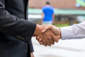 Two confident business man shaking hands during a meeting in the city