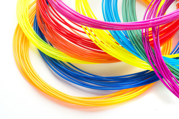 Colorful rainbow plastic filaments for 3D pen laying on white background. New toy for child.