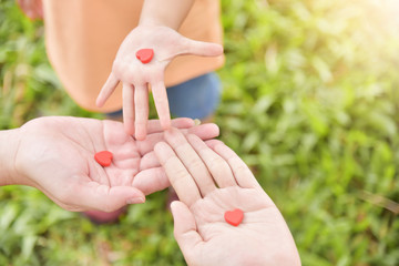 Family hands holding red hearts together.