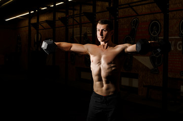 Hot shirtless man practicing crossfit in a gym