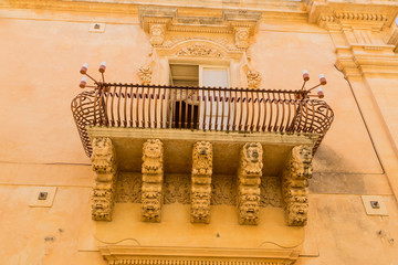 Noto, Sicily, Italy. Decorative balcony with a console of grotesque figures on the facade of the...