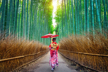 Naklejka premium Las bambusowy. Azjatycka kobieta ubrana w tradycyjne japońskie kimono w Bamboo Forest w Kioto, Japonia.