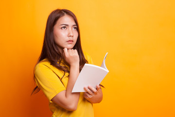 Young Asian woman with a book is thinking.