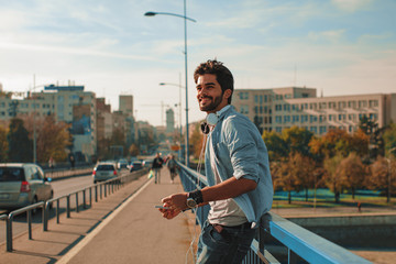 Young happy man using a smartphone  in the city