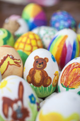 Fototapeta na wymiar Detail of colorful painted Easter eggs with different forms and animals. In that case, a bear