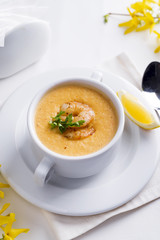 Creamy tomato soup with seafood and lemon on a white background.