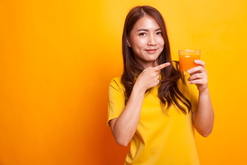 Young Asian woman point to orange juice in yellow dress