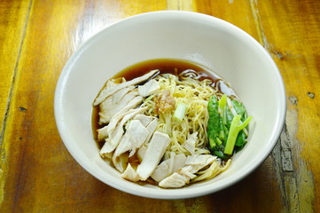 Chinese egg noodles with chicken meat in brown soup on bowl