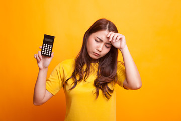 Asian woman got  headache with calculator in yellow dress