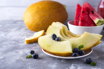 sliced ripe melon on a plate on a light stone background