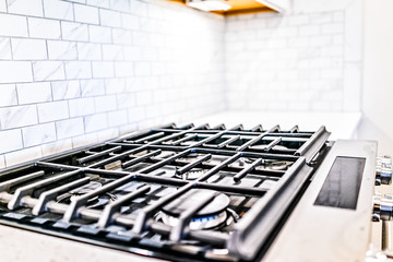 Macro closeup of modern luxury gas stove top with tiled backsplash