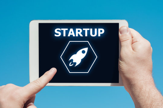 Man holding a tablet device showing startup rocket icon.
