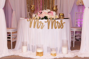 A table for the bride and groom decorated with flowers and candles with an inscription for the wedding ceremony. Side view, selective focus