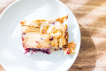 Closeup of hot red cherry cobbler banana bread piece slice cake on plate, golden crust, macro detail texture flat top view down