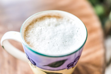 Macro closeup of coffee cup with detail, texture of soy milk bubbles white foam cappuccino