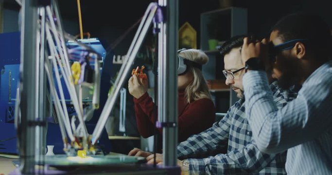 Group of multiethnic coworkers in laboratory wearing VR goggles and exploring 3d printing model. Movement 4K shot on Red cinema camera.
