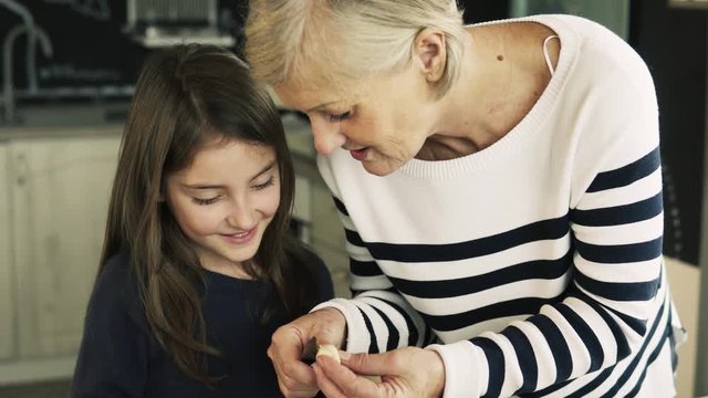 A small girl with grandmother cooking at home.