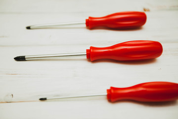 Repair carpenter tools: red screwdrivers on white old wooden background, copy space