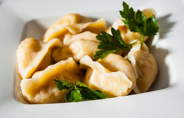 Meat dumplings - russian pelmeni, ravioli with meat on plate on a wooden background