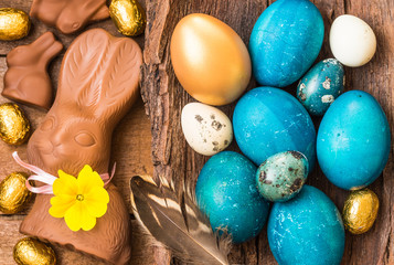 Fototapeta na wymiar Easter blue eggs, chocolate bunnies and candies on wooden background.