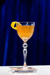 Glass with orange cocktail with slice of orange on bar counter, selective focus