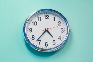 white steel clock on green pastel concrete wall background in living room