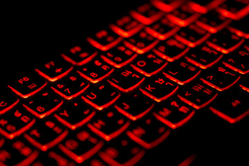 Diagonally Thai - English language laptop keyboard with glowing red light for hacking ,gaming,program developing concept,soft focus