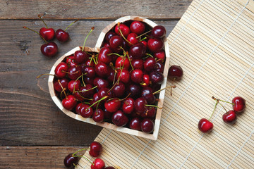 Cherry heart - delicious sweet cherries in a heart-shaped wooden bowl