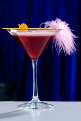 Alcoholic pink cocktail in a martini glass with straw, shallow dof