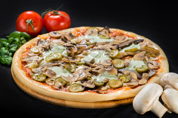 Classic delicious Italian pizza with mozzarella, mushrooms, eggplants, pickled cucumbers and sauce on wooden board on dark background