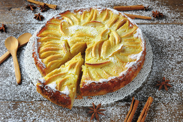Baked apple pie cake dessert covered with icing sugar on wooden background