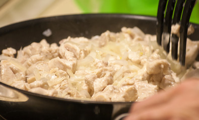 Fried chicken with onions and carrots in a frying pan