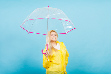 Happy woman wearing raincoat holding transparent umbrella
