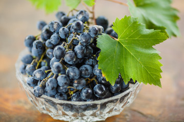 fresh juicy ripe grapes with green leaves in a white bowl, wine making