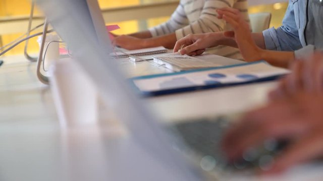Closeup of students hands working on laptop in class
