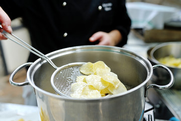 Chef cooking delicious french fries in a pot