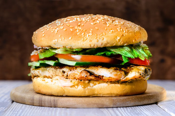 Delicious tasty burger with beef, tomatoes, salad and sauce on board on wooden  background, close-up
