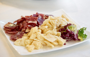 Parmesan cheese, cold cuts and red chicory salad in a plate