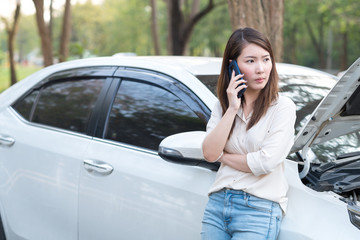 Young Asian woman try to call assistance for her broken down car