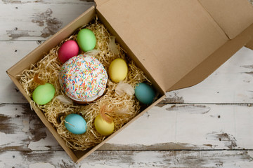Easter cake and colorful painted eggs in a box