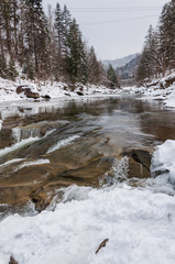 Fototapeta na wymiar Winter landscape. Mountain river flows from the rocks. Snow and mountain river
